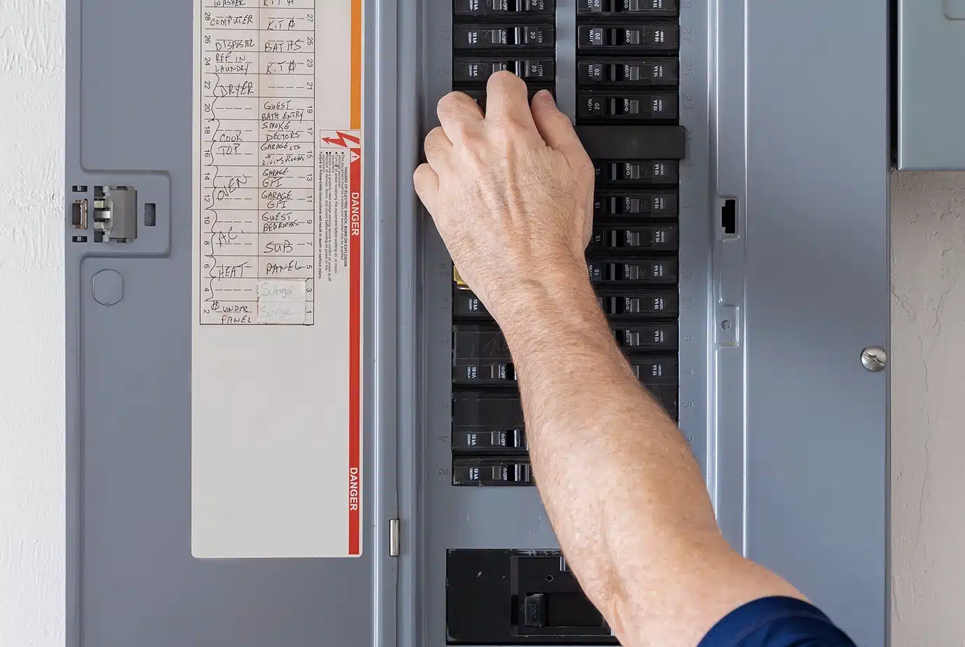 Electrician turning off power for electrical outlet at circuit breaker box.